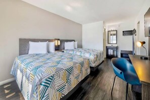 Une chambre d’hôtel avec deux lits, un bureau, une chaise, un miroir et une table de chevet.