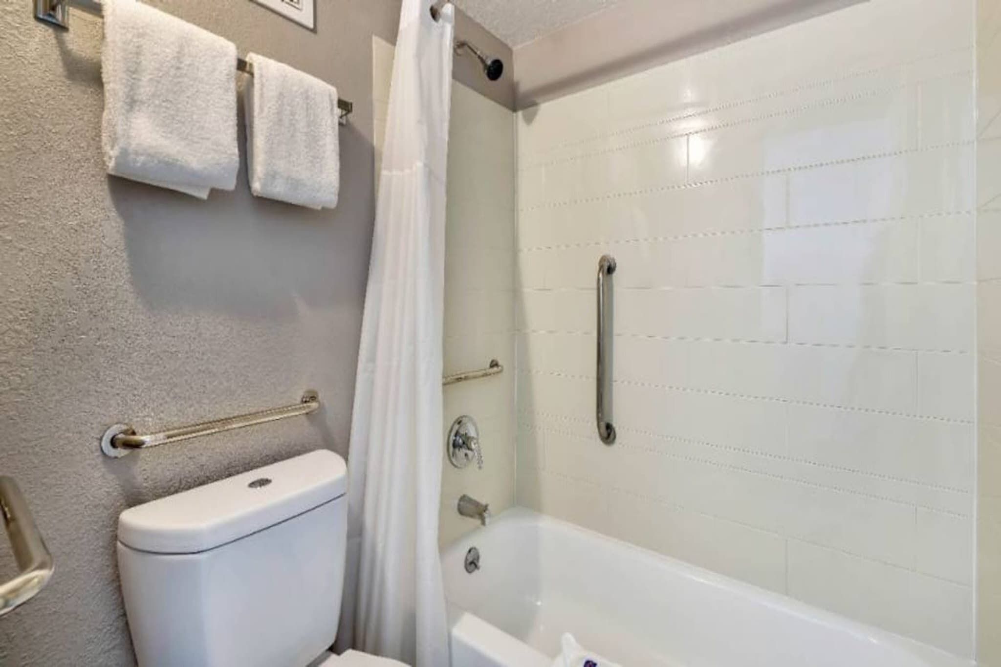A bathroom with a toilet, a shower with a glass door, and a bathtub.