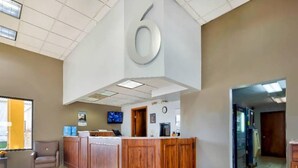 A reception area with a wooden counter, a clock, and a television. - 2 Queen Beds | Suite, Nsmk, Kitchen (Effingham)
