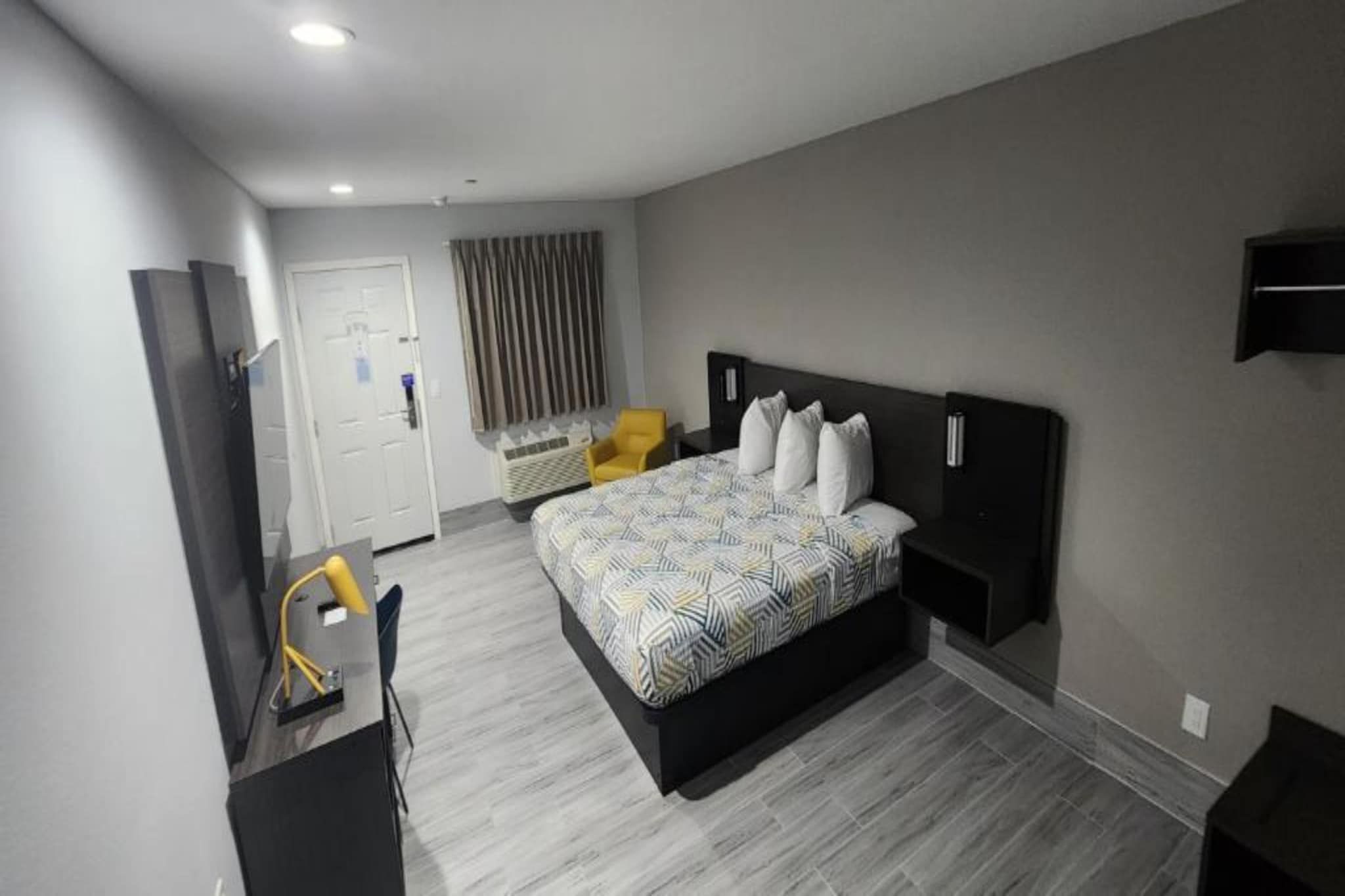 Una habitación de hotel moderna con una cama grande, un escritorio y una silla.