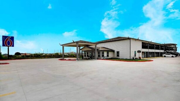 A gas station with a large building, a covered parking area, and a clear sky. - 1 King Bed | Non-Smoking (Aransas Pass)
