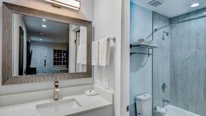 A modern bathroom with a large mirror, a sink, a toilet, and a shower. - 1 King Bed | Non-Smoking (Aransas Pass)