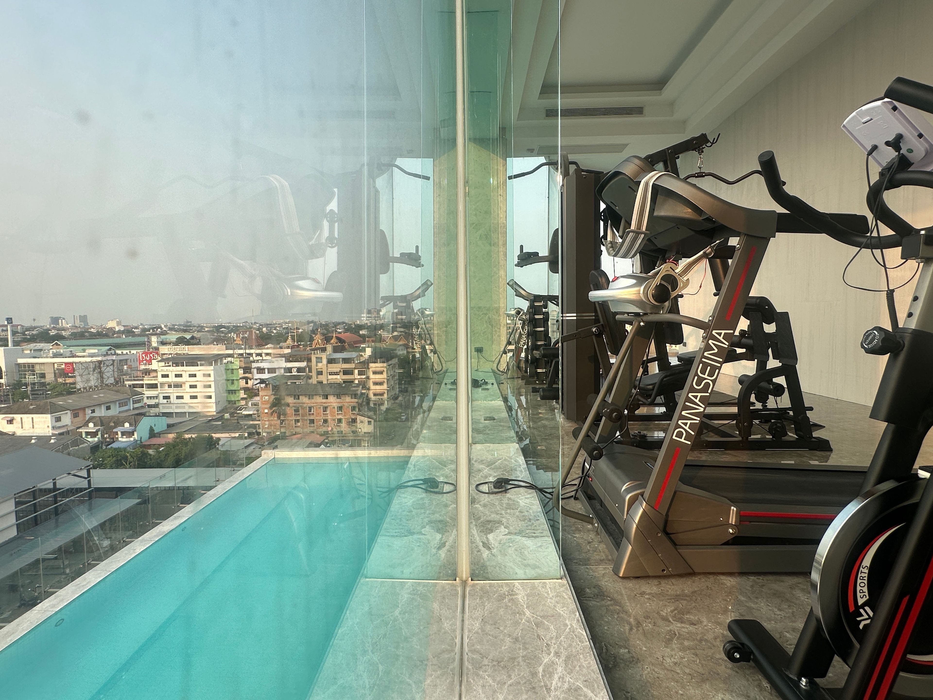 A gym with exercise equipment and a view of a cityscape through a glass wall.