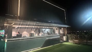 A bar with a sign reading 'OCO Sky Bar & BBQ' at night.