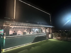 A bar with a sign reading 'OCO Sky Bar & BBQ' at night.