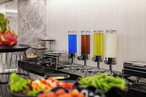Zona de bufé con diferentes opciones de comida y dispensadores de bebidas de colores.