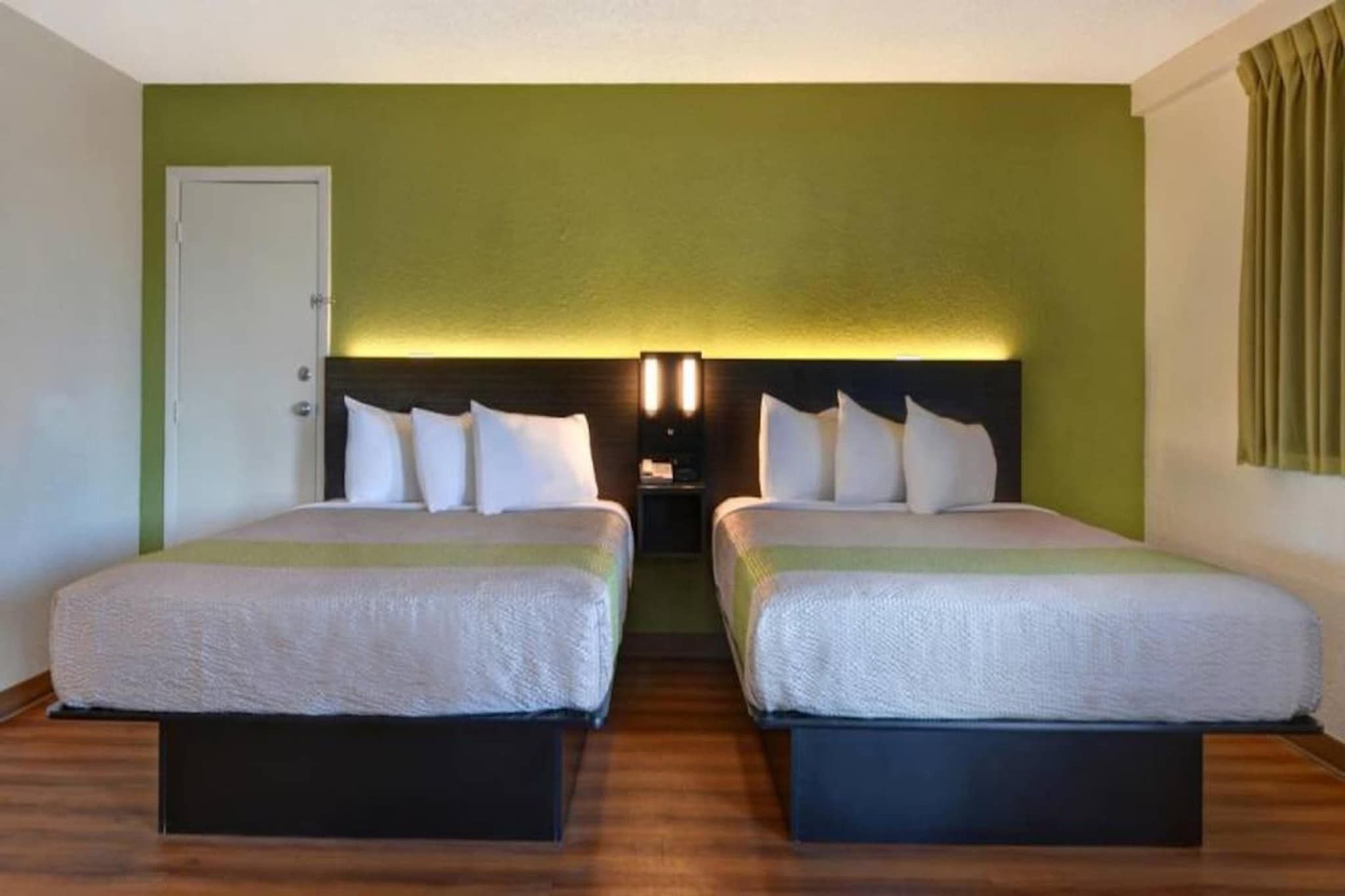 Una habitación de hotel con dos camas, una mesita de noche y una puerta.