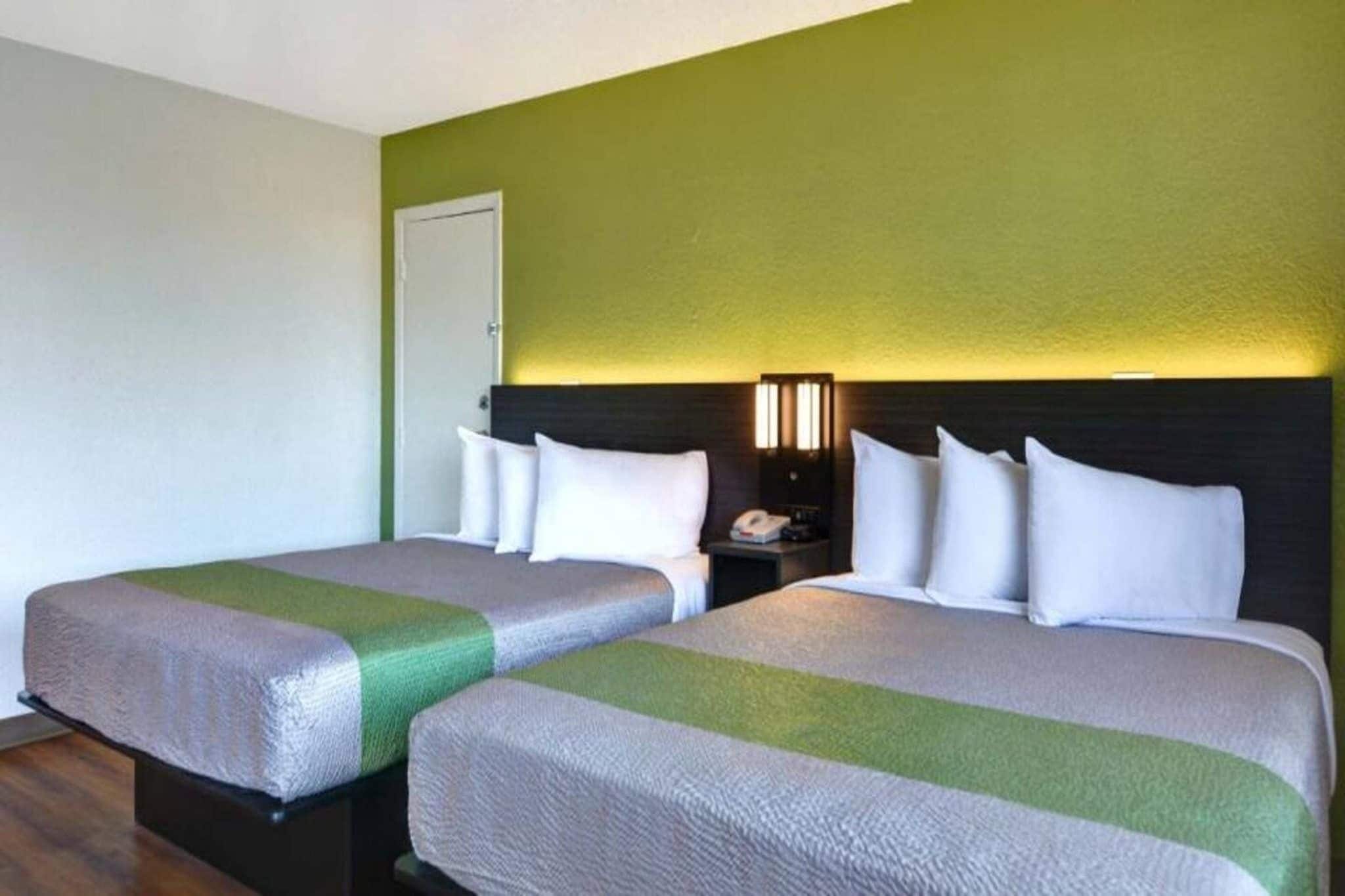 Une chambre d’hôtel avec deux lits, une table de chevet, une lampe et une porte.