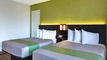 Una habitación de hotel con dos camas, una mesita de noche, una lámpara y una puerta.