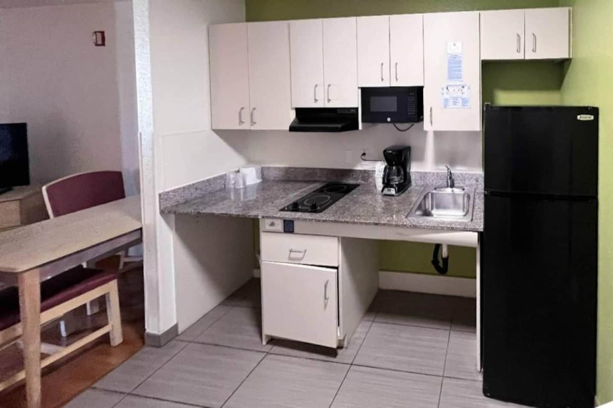 A compact kitchen with a microwave, coffee maker, and a refrigerator.