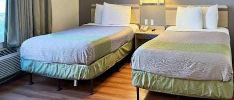 Une chambre d’hôtel avec deux lits simples, une table de chevet avec une lampe et une fenêtre avec des rideaux.