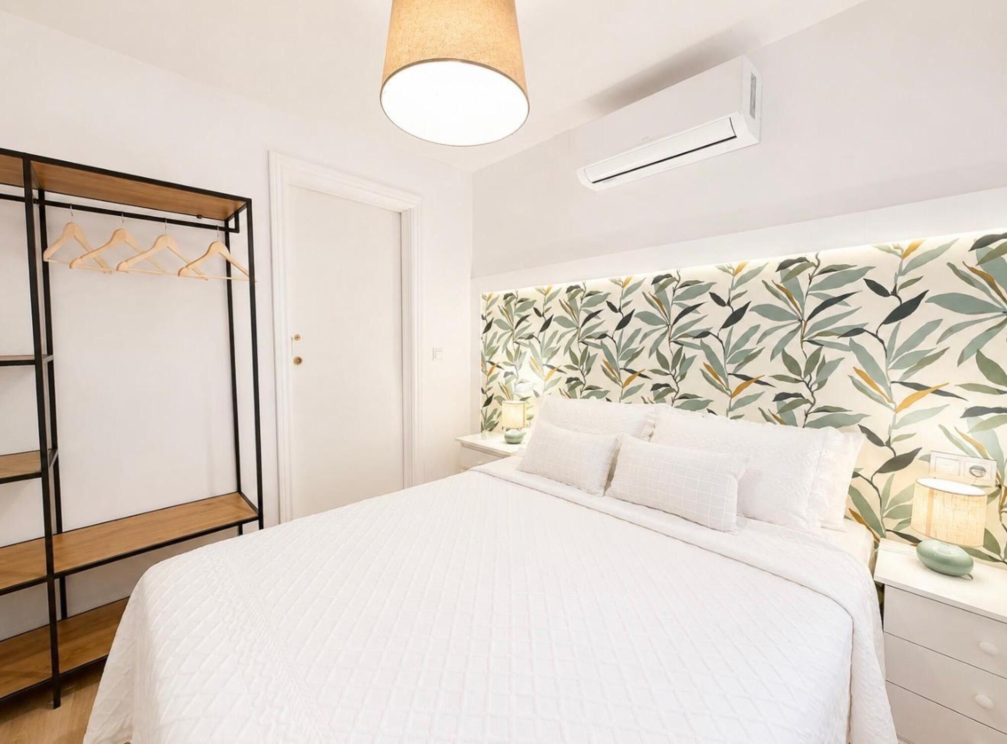 Une chambre à coucher avec un lit, une armoire et un mur orné d’un motif végétal.
