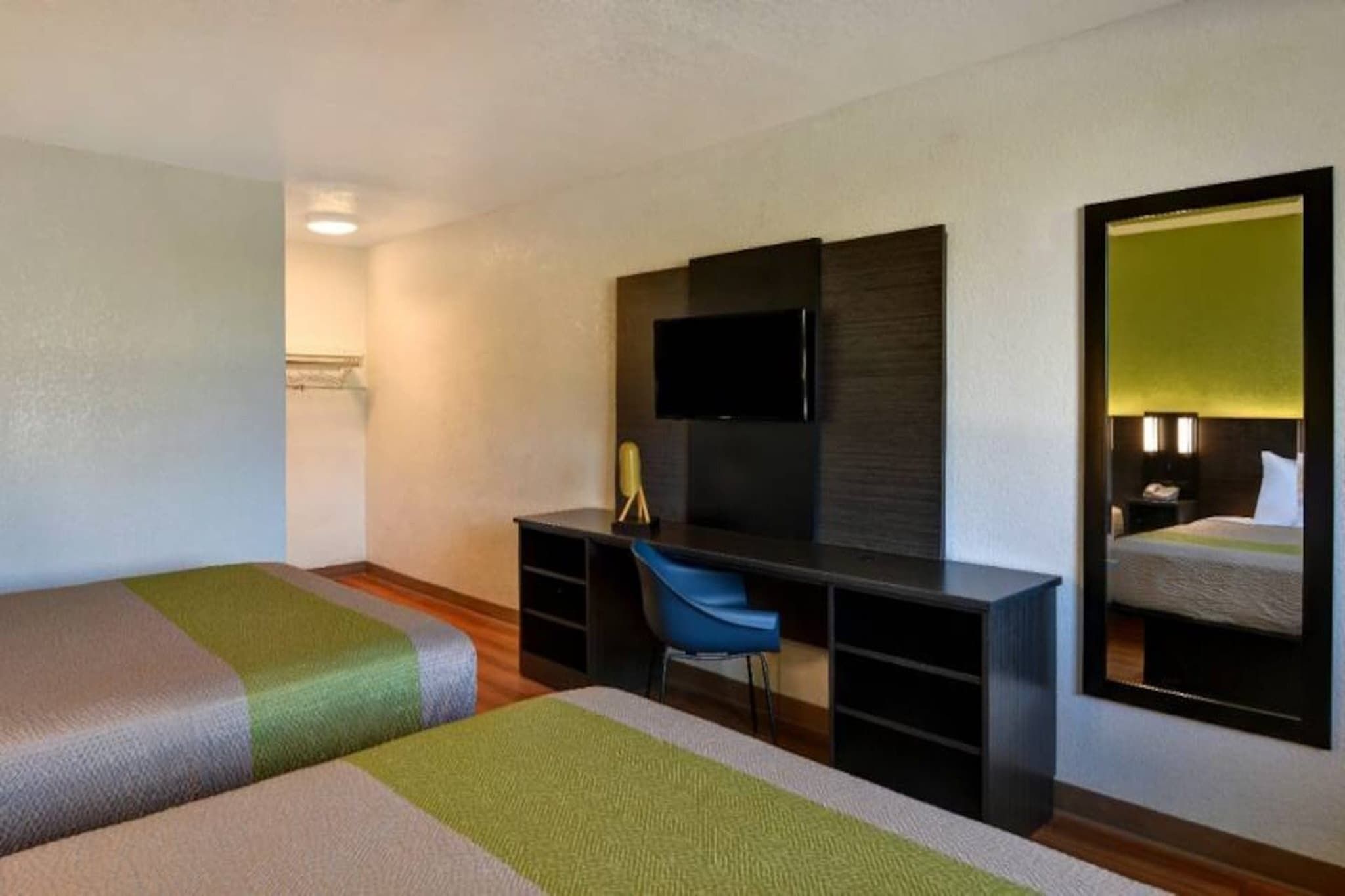 Een hotelkamer met twee eenpersoonsbedden, een bureau met stoel, een flatscreen televisie en een grote spiegel.