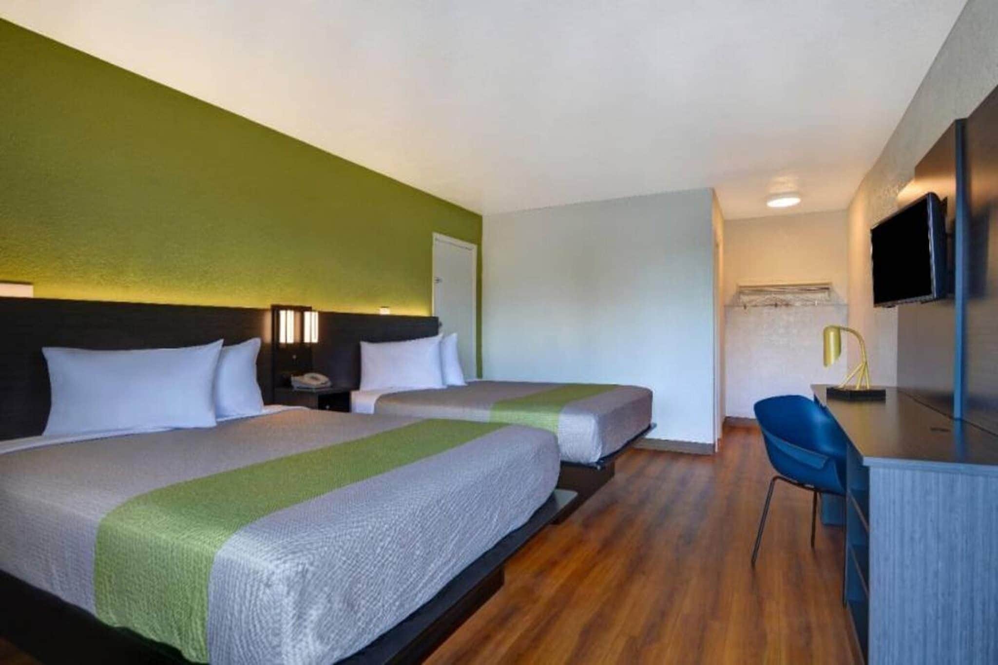 Een hotelkamer met twee bedden, een bureau, een stoel en een televisie.