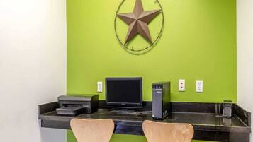 A reception desk with a computer monitor, printer, and speaker, against a green wall with a star decoration.
