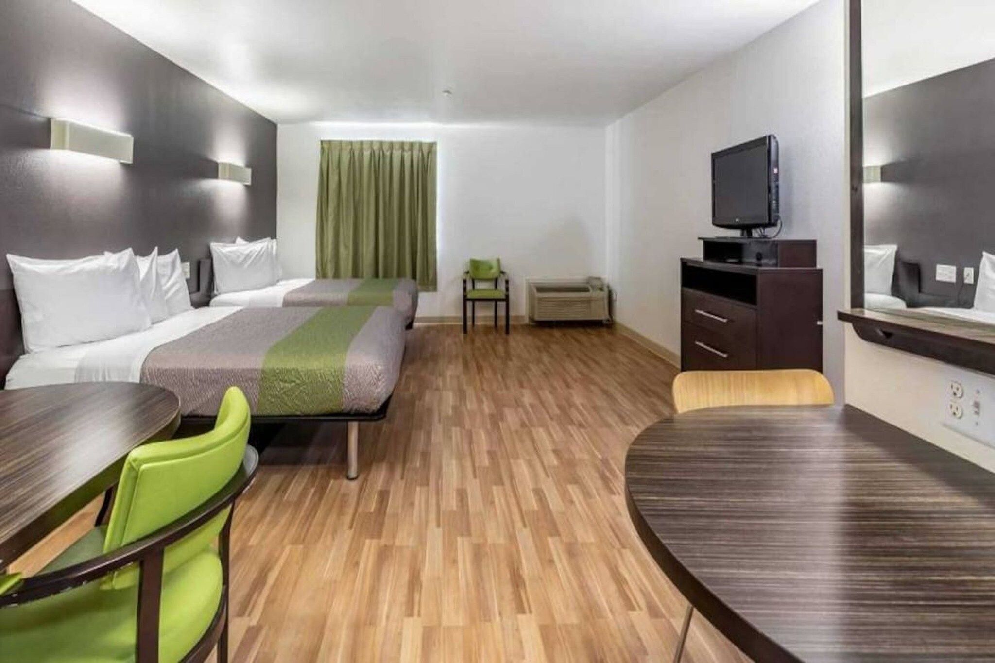 A hotel room with two beds, a TV, a desk, and a chair.