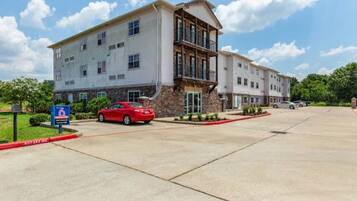 A multi-story hotel with a stone facade and a red car parked in front.