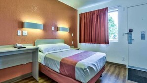 A hotel room with a bed, bedside table, and a window with curtains. - ADA Full Bed|Tub|Micfridge (Flaggstaff)