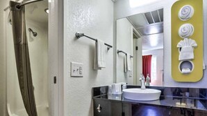A bathroom with a shower, a sink, and a mirror. - ADA Full Bed|Tub|Micfridge (Flaggstaff)