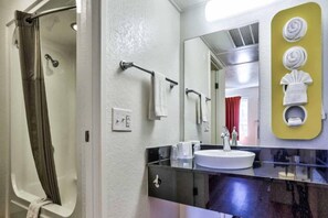 Un baño con ducha, lavabo y espejo.