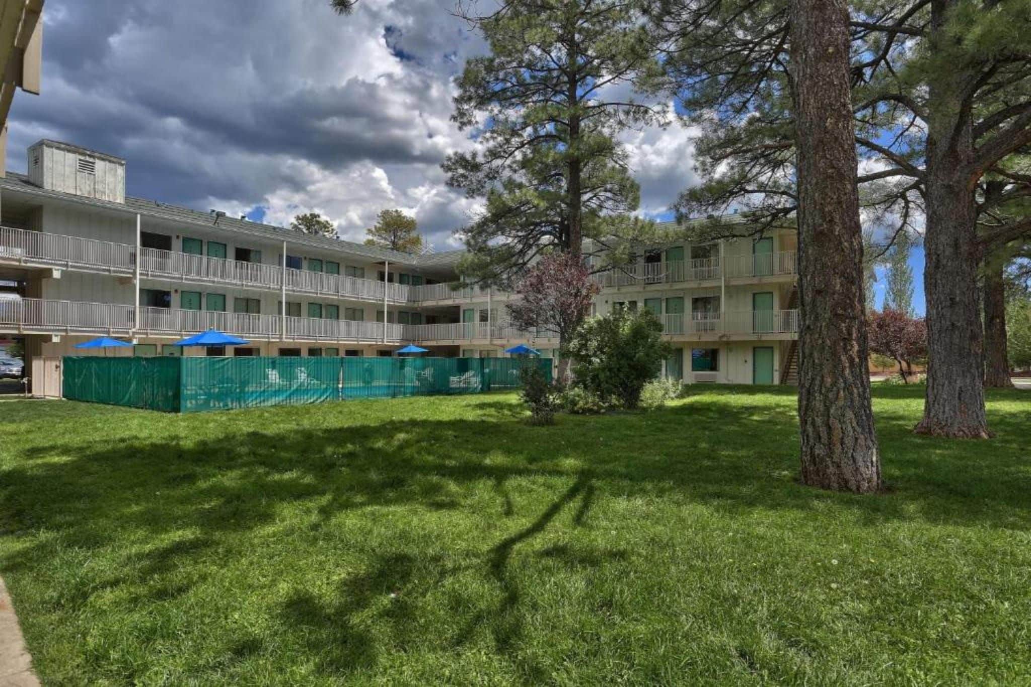 Un immeuble à plusieurs étages doté de balcons, entouré d’une pelouse bien entretenue et d’arbres.