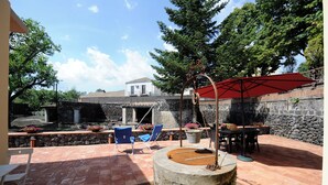 A patio area with a stone wall, a red umbrella, and outdoor seating. - Vrbo Property (Fornazzo)