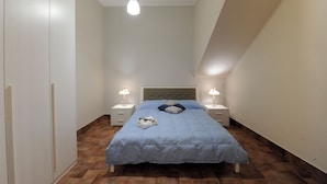 A bedroom with a bed, two bedside tables with lamps, a wardrobe, and a hanging light fixture. - Vrbo Property (Fornazzo)