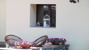 A building with a window displaying birdcages and a light fixture. There are wicker chairs and flower pots outside. - Vrbo Property (Fornazzo)