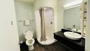 Un baño con inodoro, cabina de ducha y lavamanos.
