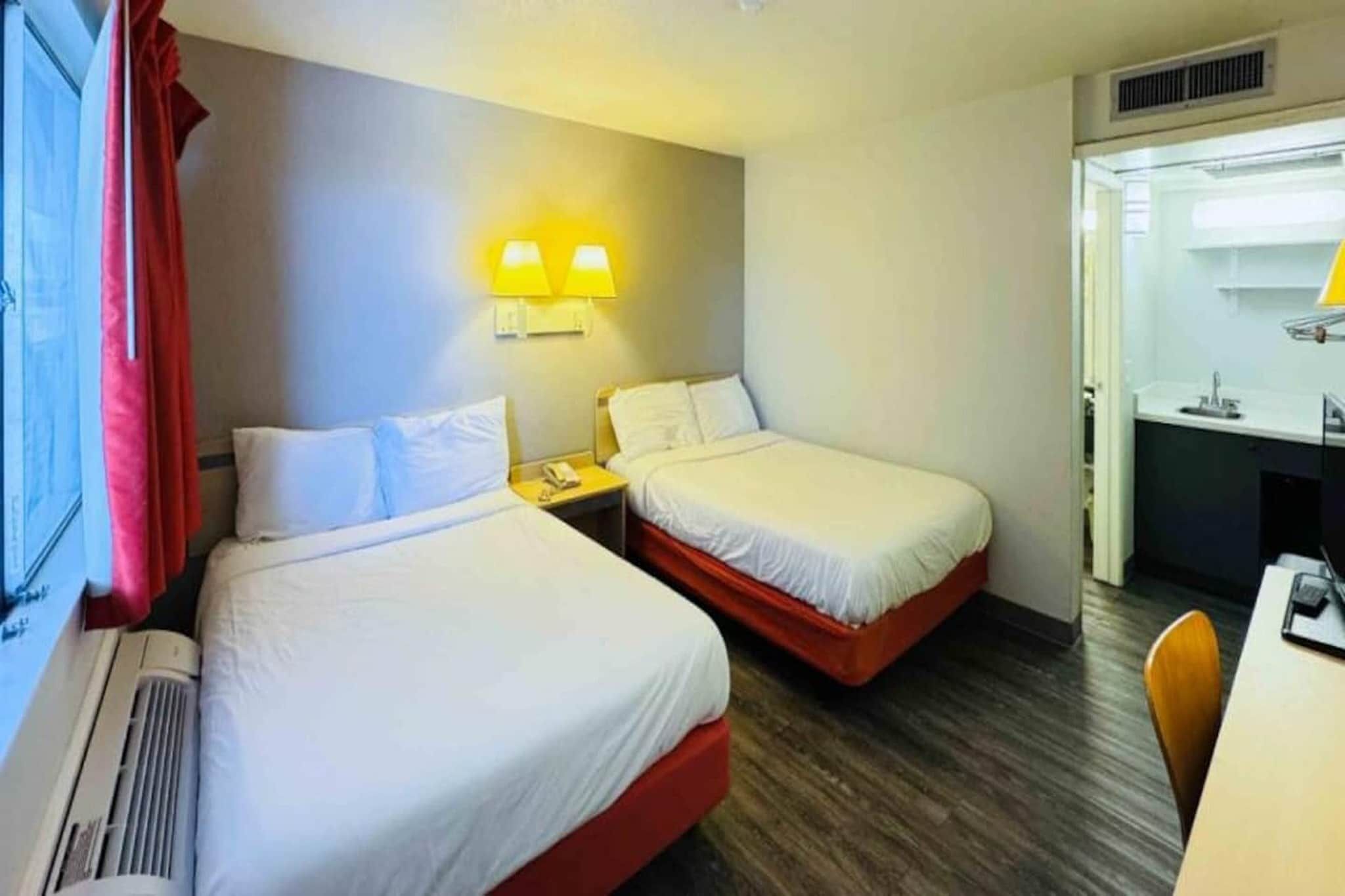Hotellihuone, jossa on kaksi sänkyä, työpöytä ja tuoli.