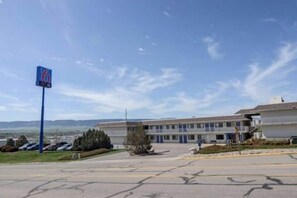 Un motel con un amplio estacionamiento, un letrero y un edificio con múltiples ventanas.
