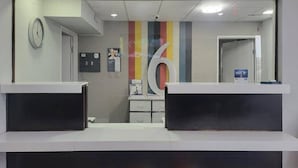 En receptionsdisk med et stort nummer 6 på væggen, et ur og en opslagstavle med meddelelser.
