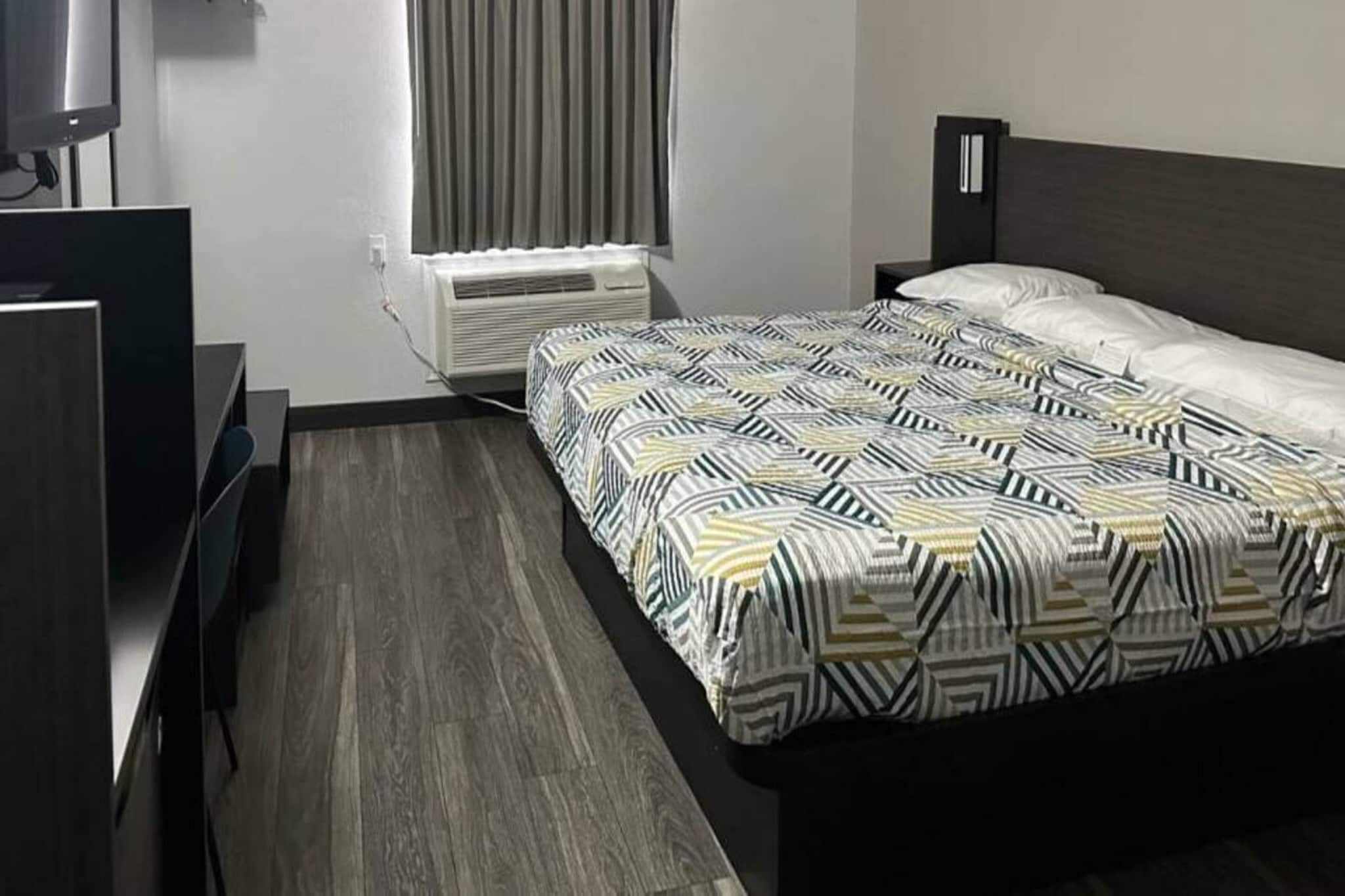 Une chambre d’hôtel équipée d’un lit, d’un bureau, d’une chaise, d’une télévision et d’un appareil de climatisation.