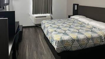 Une chambre d’hôtel équipée d’un lit, d’un bureau, d’une chaise, d’une télévision et d’un appareil de climatisation.