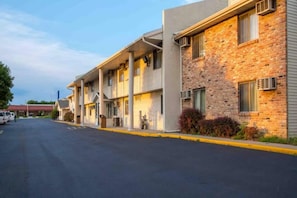 Fila de edificios de motel con camino pavimentado y coches aparcados.