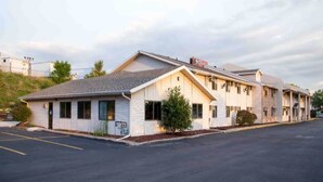 Ein Motel mit eingeschossiger Bebauung, einem Parkplatz davor und einer hügeligen Landschaft im Hintergrund.