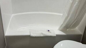 Eine weiße Badewanne mit Handtuch am Rand und einem teilweise geöffneten Duschvorhang.