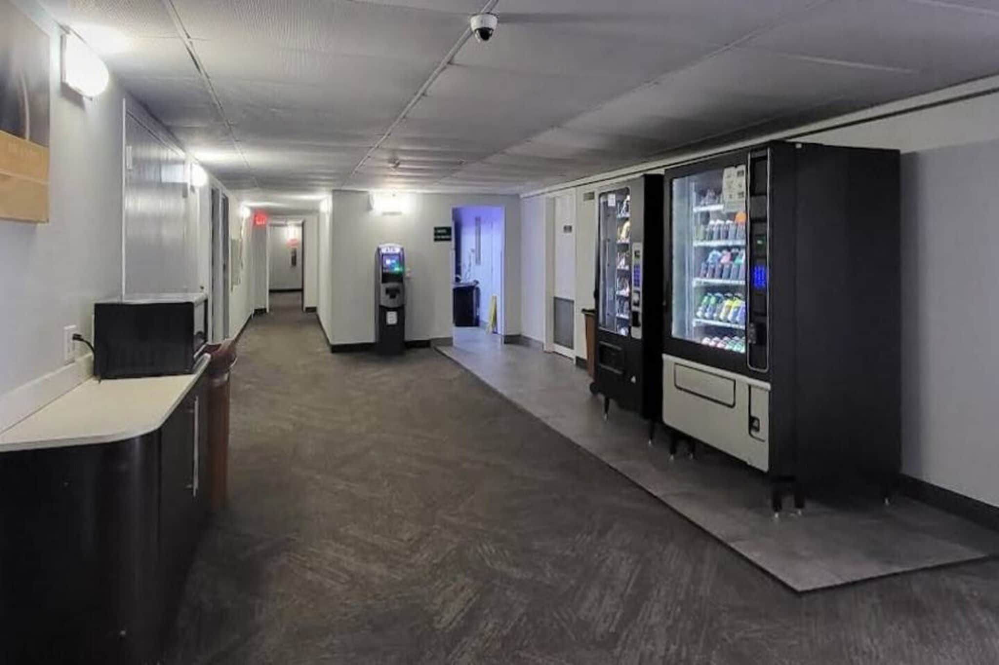 A hallway with vending machines, a reception desk, and a security camera on the ceiling.