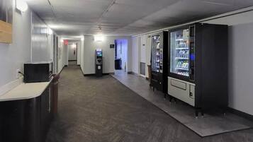 A hallway with vending machines, a reception desk, and a security camera on the ceiling.