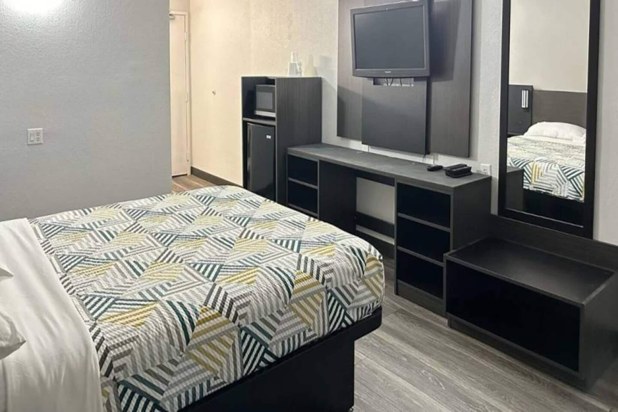 A hotel room with a bed, a TV, a desk, and a wardrobe.