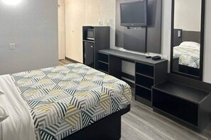 Una habitación de hotel con cama, televisión, escritorio y armario.
