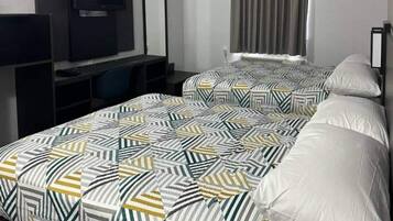 Une chambre d’hôtel avec un lit, une télévision et un bureau.