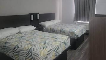 Une chambre d’hôtel avec deux lits, chacun doté d’une literie à motifs, d’une tête de lit sombre et d’une fenêtre avec des rideaux.