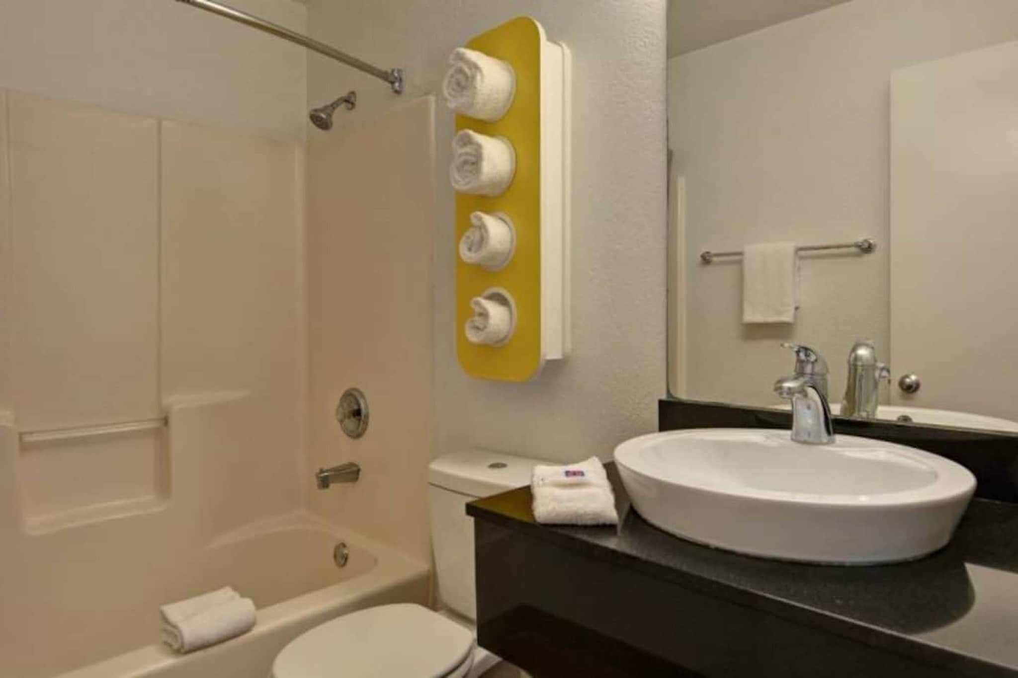 Ein Badezimmer mit einer Badewanne, einer Toilette, einem Waschbecken und einem Spiegel.