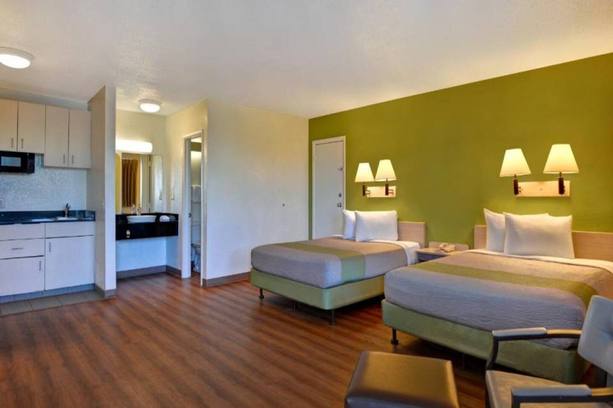 Ein Hotelzimmer mit zwei Betten, einer Küchenzeile und einem Badezimmer.