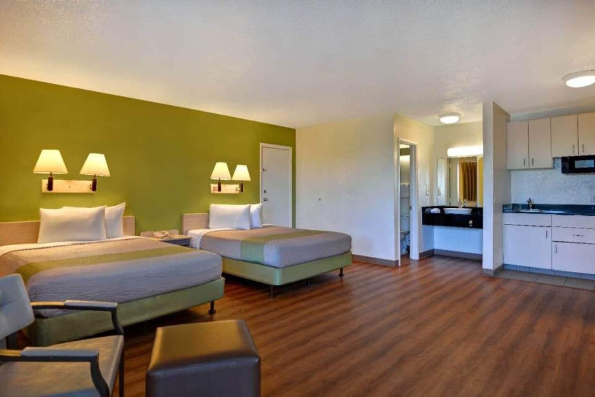 Een hotelkamer met twee bedden, een kitchenette en een badkamer.