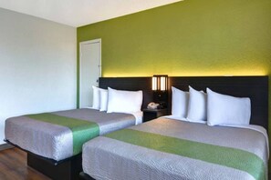 Ein Hotelzimmer mit zwei Betten, einem Nachttisch, einer Lampe und einer Tür.