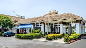 A commercial building with a tiled roof, a blue awning, and a parking lot.