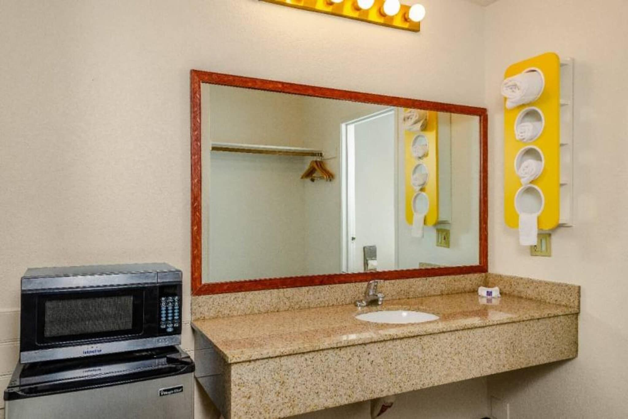 A bathroom with a sink, mirror, and a microwave.