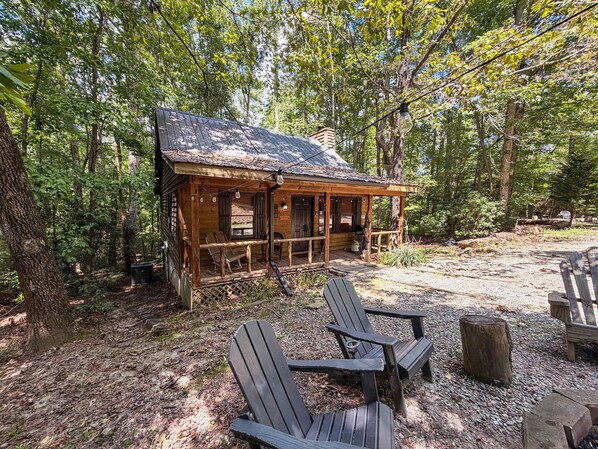 Eine rustikale Holzhütte mit Veranda, zwei Adirondack-Stühlen und Kiesgrund.